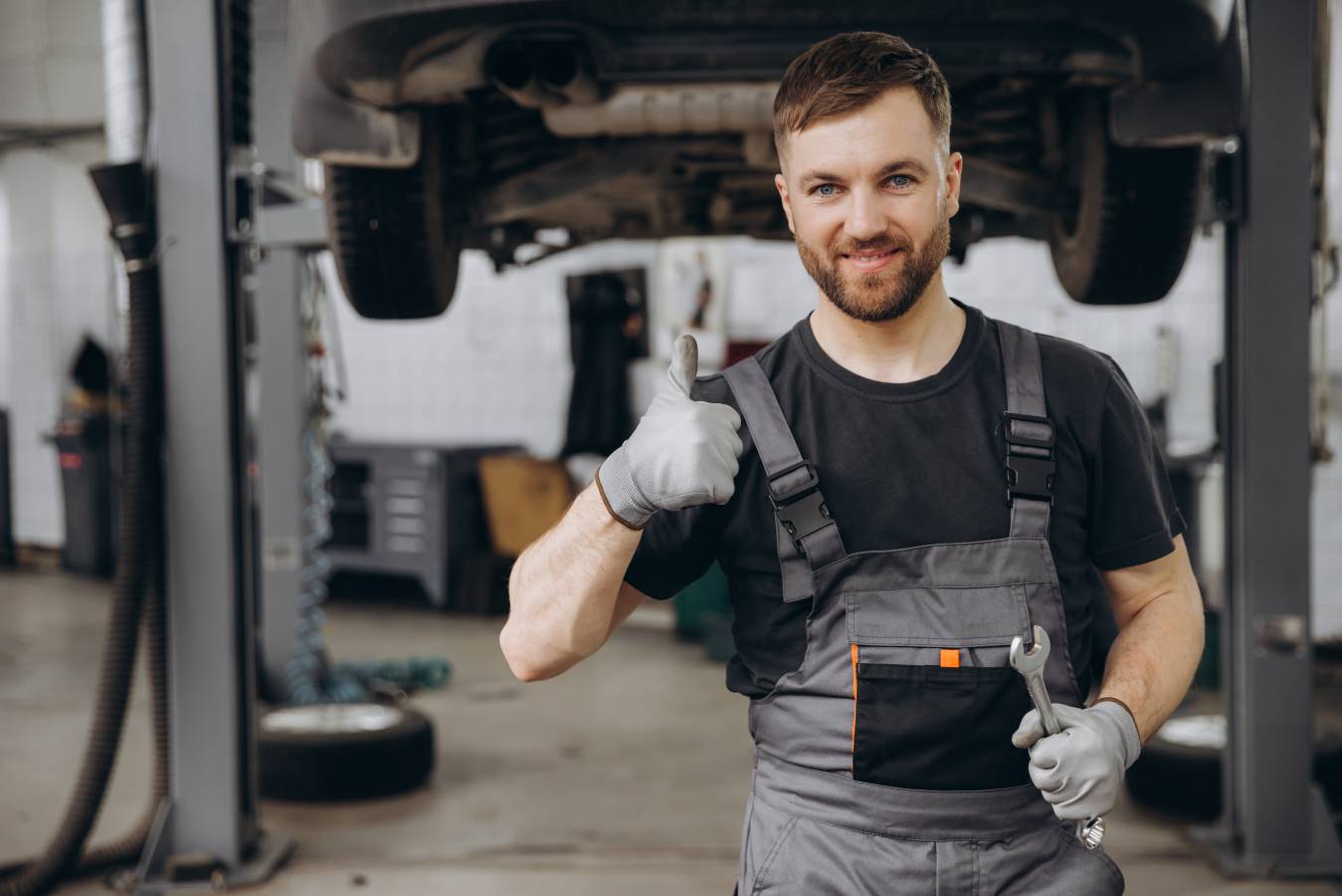 smiling-bearded-mechanic-while-standing-with-crossed-arms-holding-wrenches-car-service.jpg